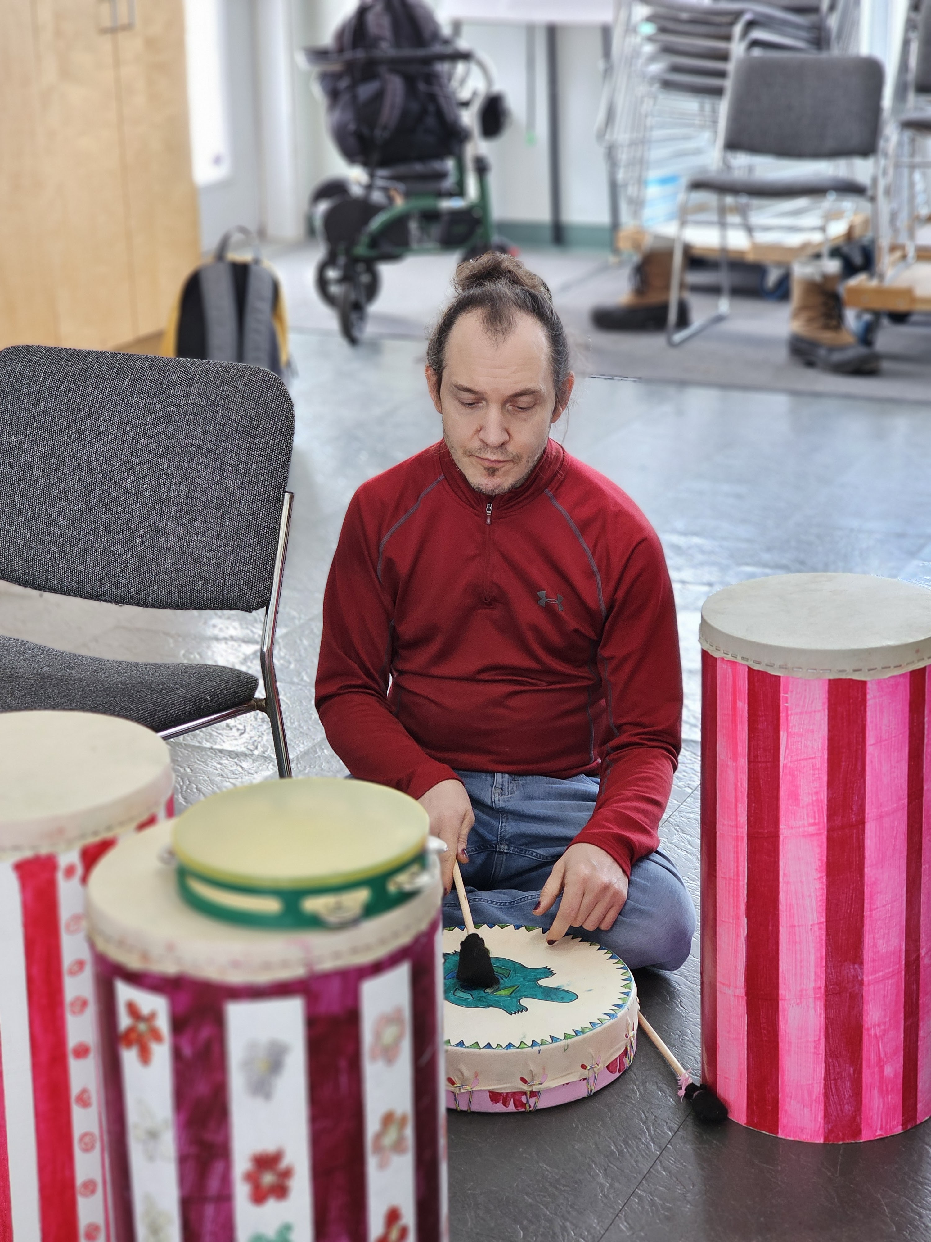 un membre de cœur qui assis sur le plancher avec un tambour et les tambours qui est autour de lui