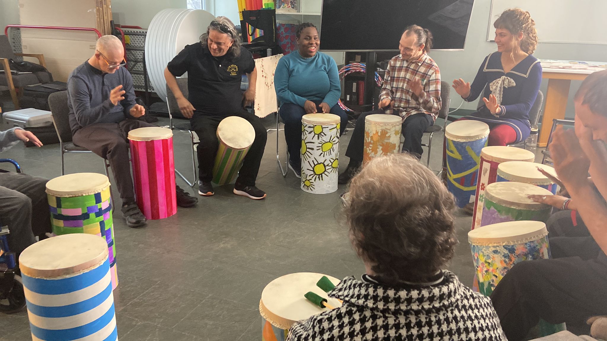 un groupe de personnes assis dans un cercle est jouent les tambours