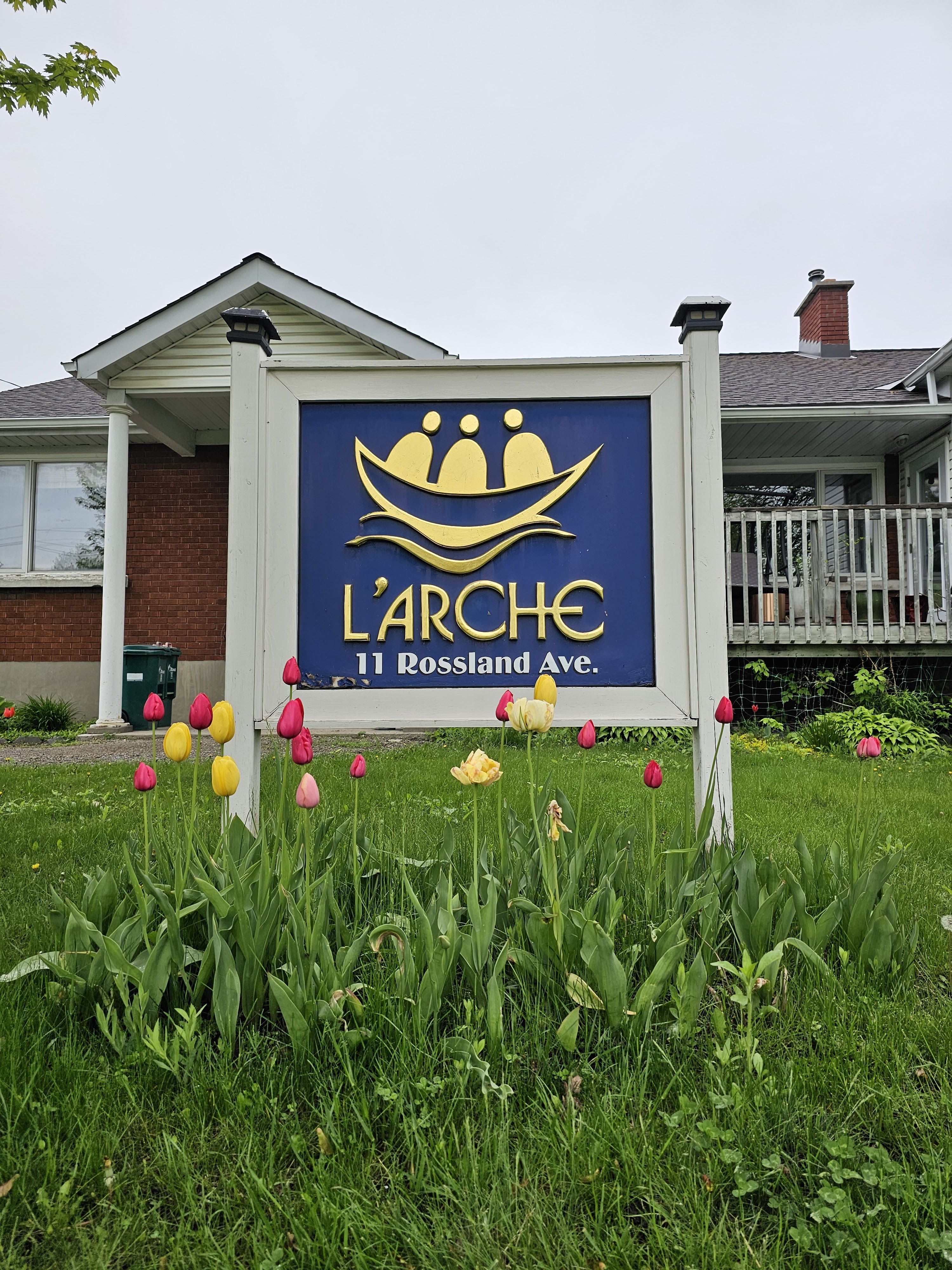 un signe de L'Arche Ottawa en avant du bureau avec les tulipes rouge et jaune autour