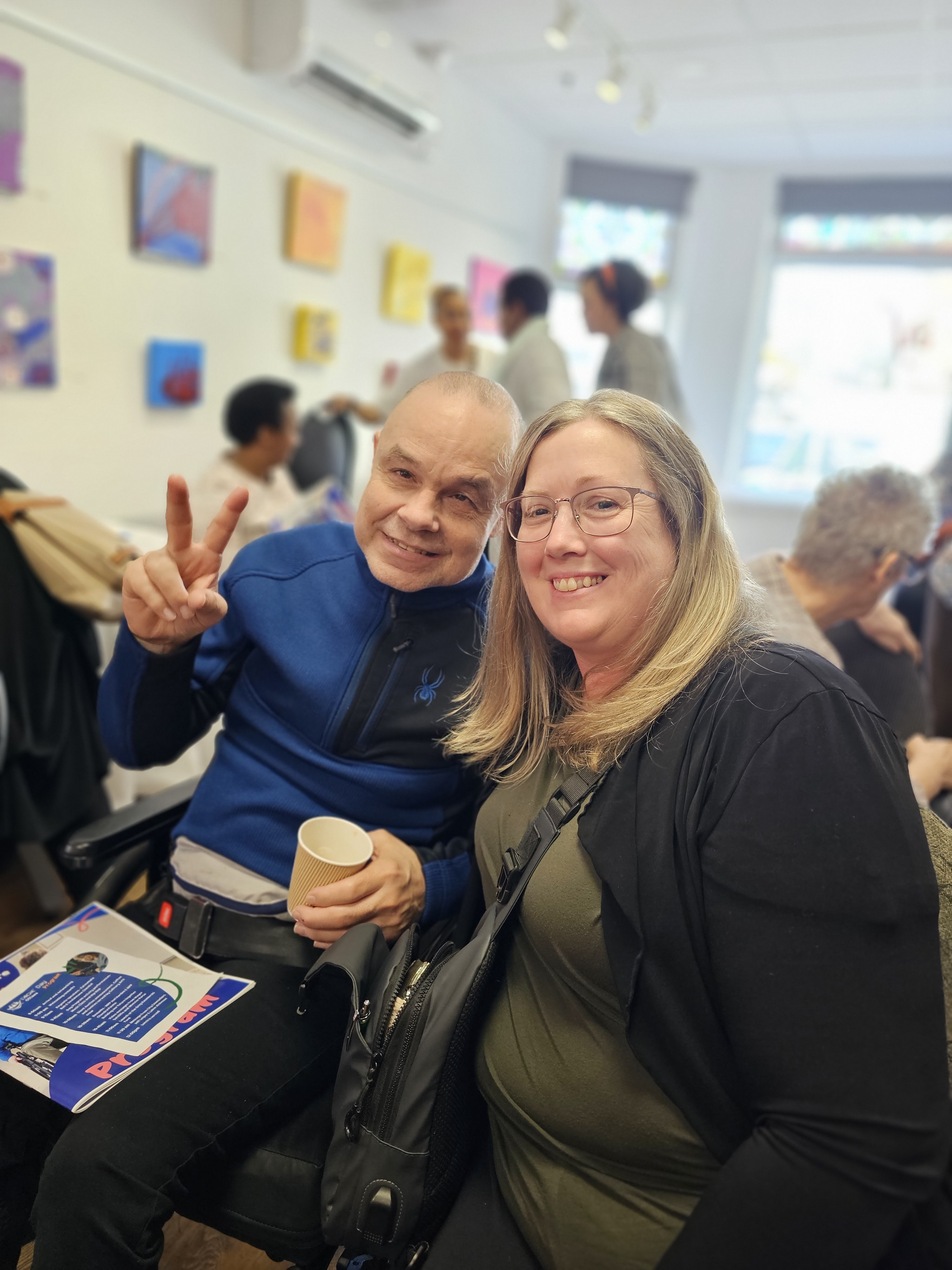 deux personnes posent pour le caméra, un qui fait un signe de paix avec son main