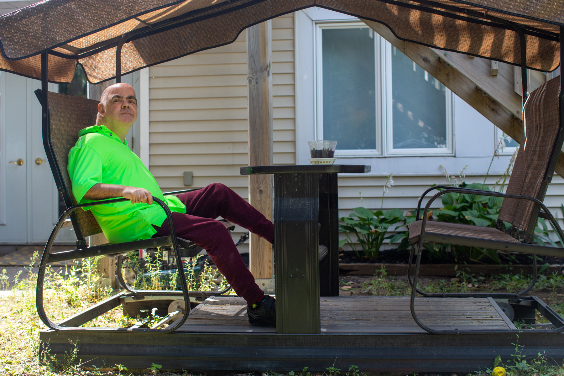 un membre de cœur qui est assis dehors sur le patio dans un chemise vert vibrante