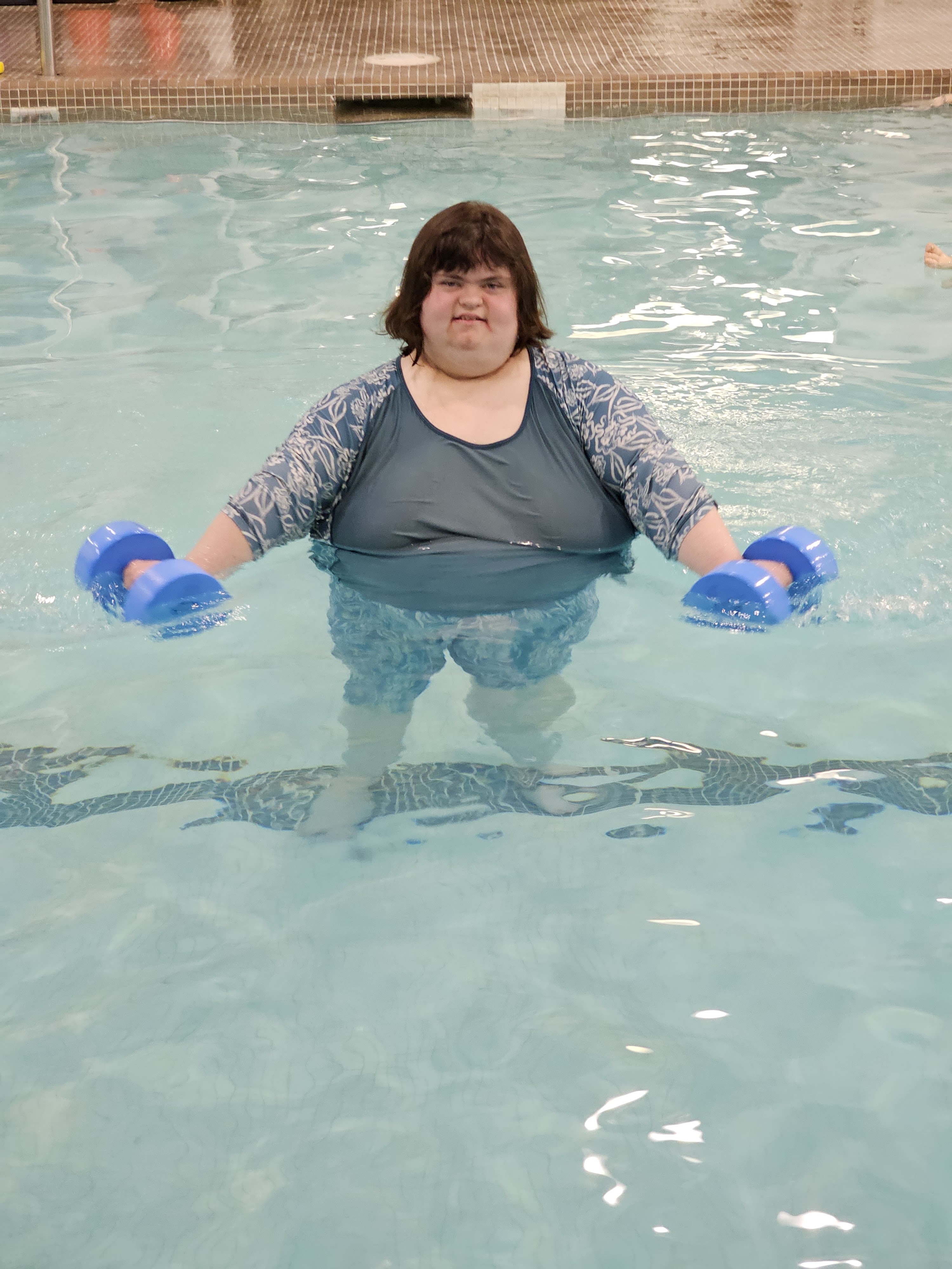 un membre de cœur est dans un piscine avec les flotteurs bleu dans ses mains
