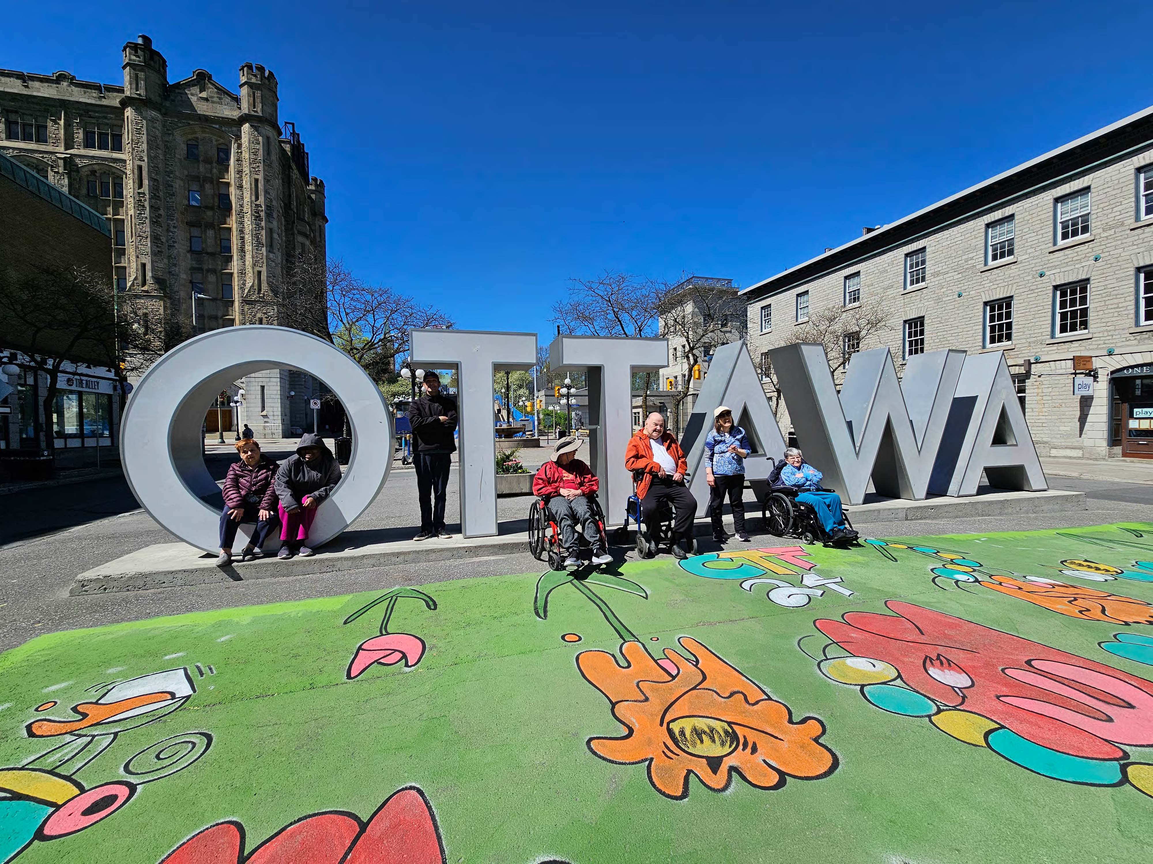 un groupe de personnes posent avec un signe d'Ottawa au centre-ville