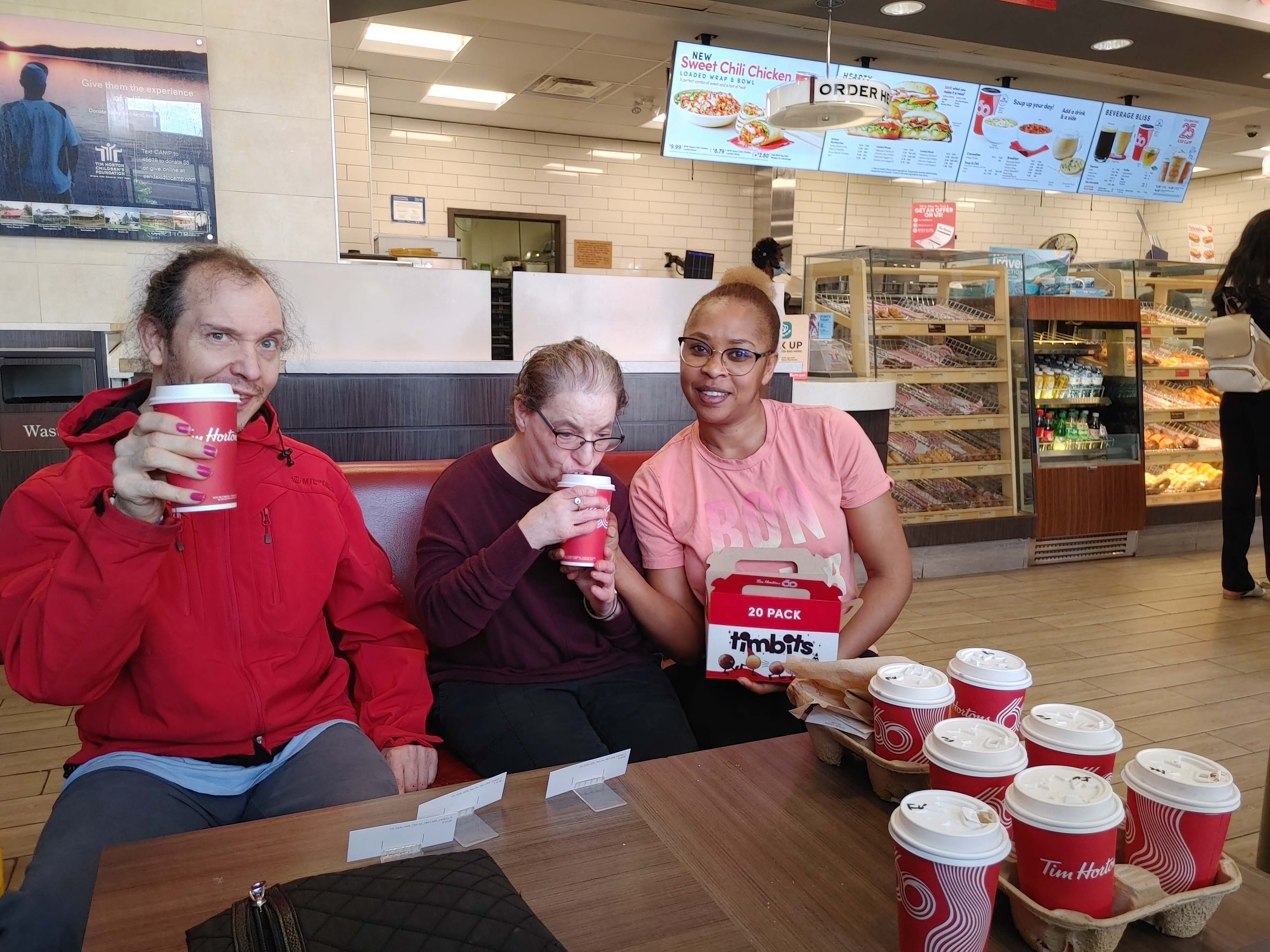 un groupe de personnes est assis dans un Tim Hortons avec du café et les beignes